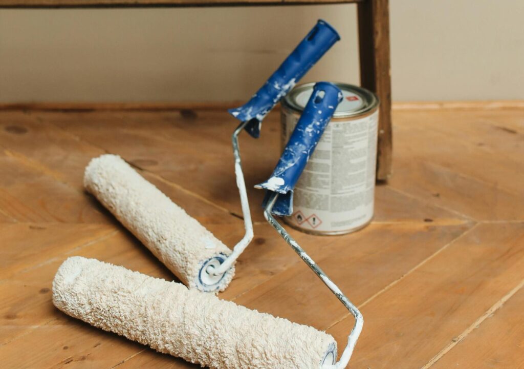 Paint rollers and can on a wooden floor, perfect for DIY home renovation projects.
